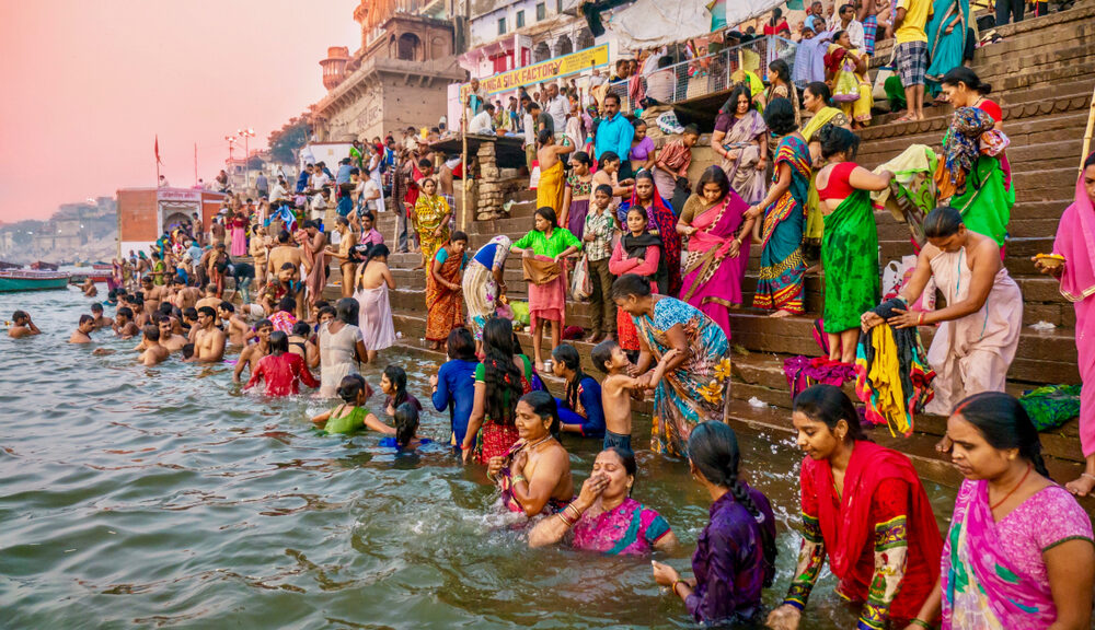 people of faiths gathered on river bank india multicolored clothes wash